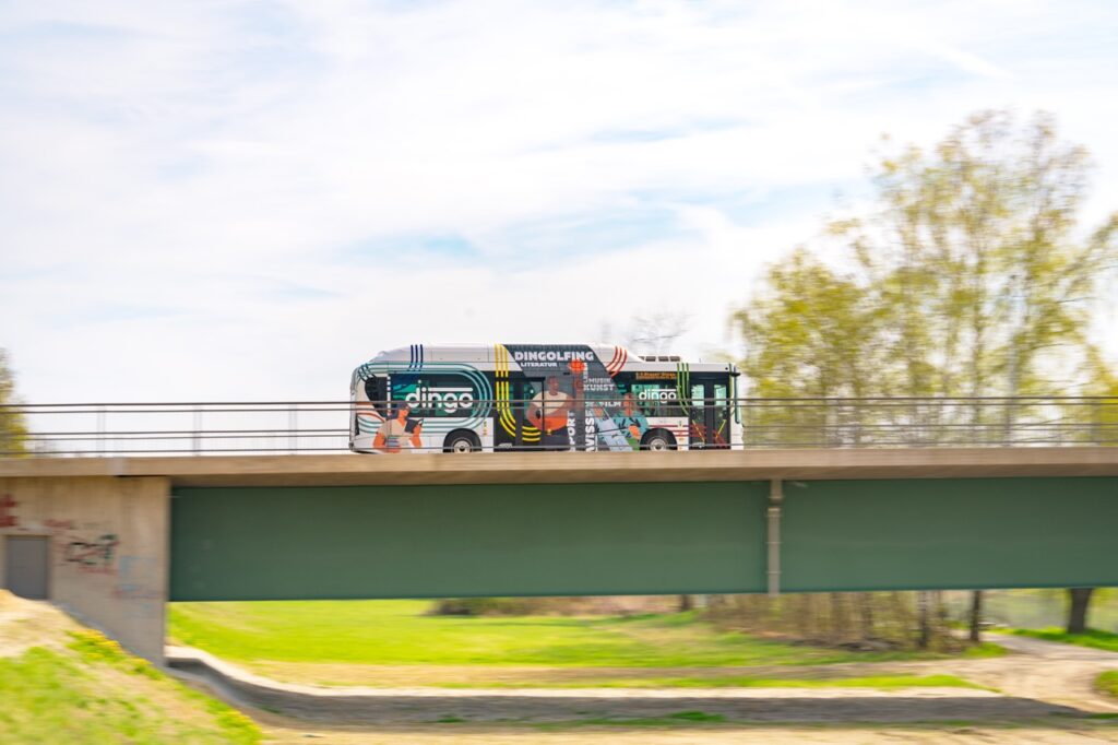 Weißer Dingo, einer der Dingolfinger Stadtbusse, fährt über die Isarbrücke.