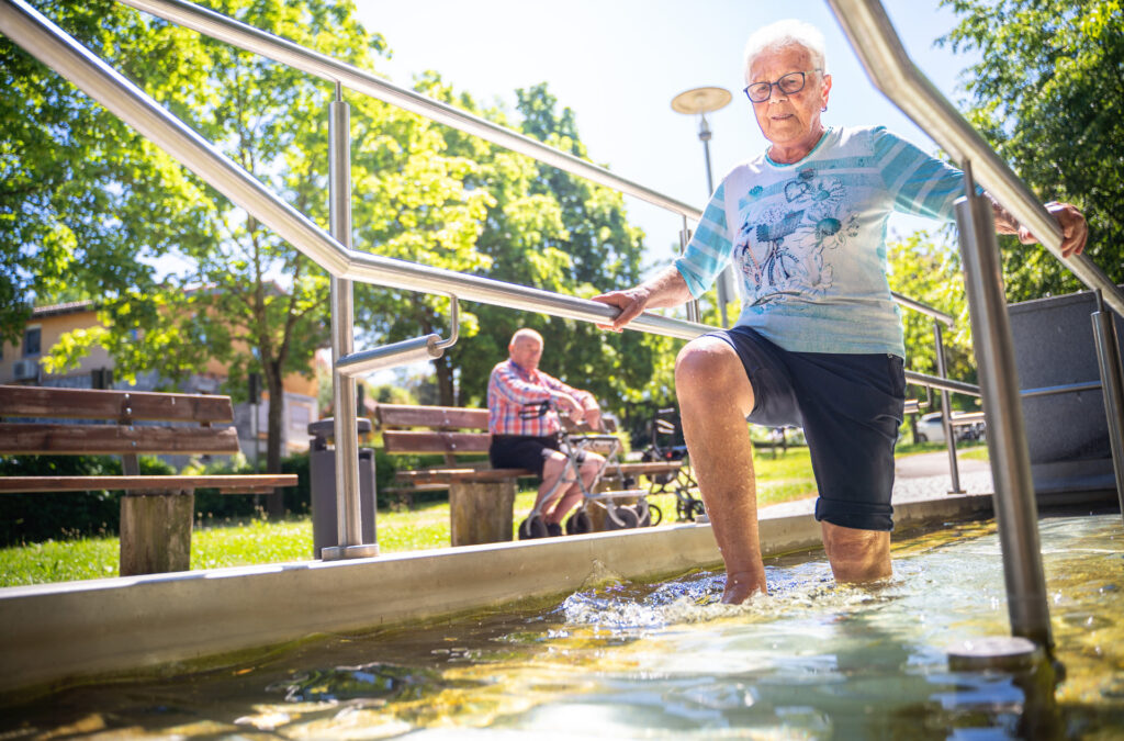 Ältere Dame steigt durch Wasserbecken im Freien