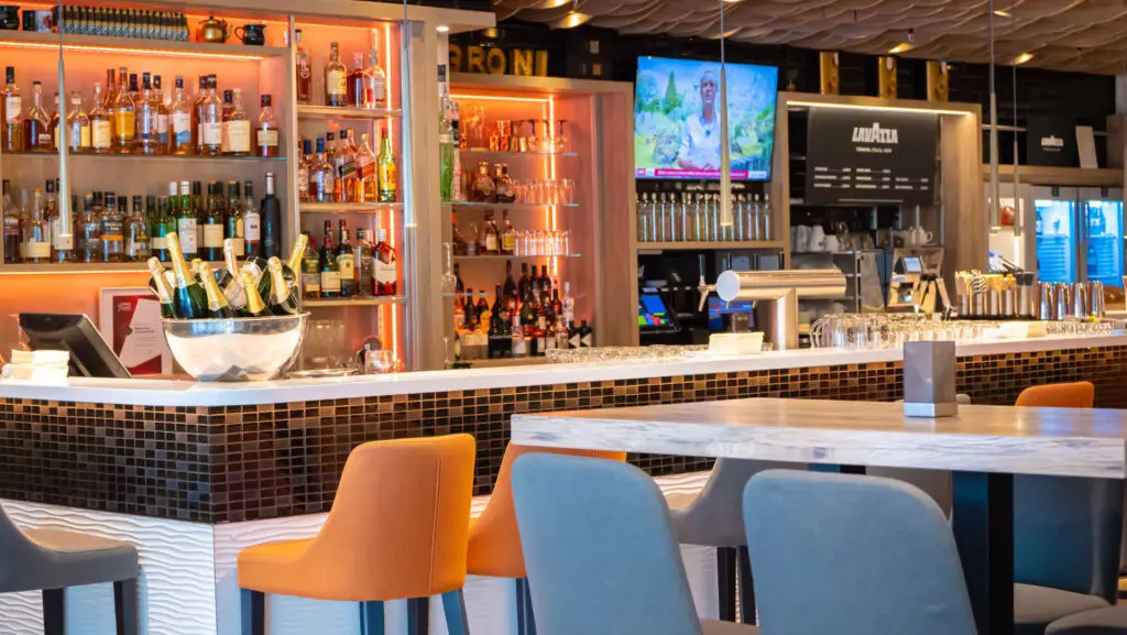 Der Tresen der Bar im Holiday Inn Munich City Center mit verschiedenen Flaschen und Gläsern und Barhockern im Vordergrund