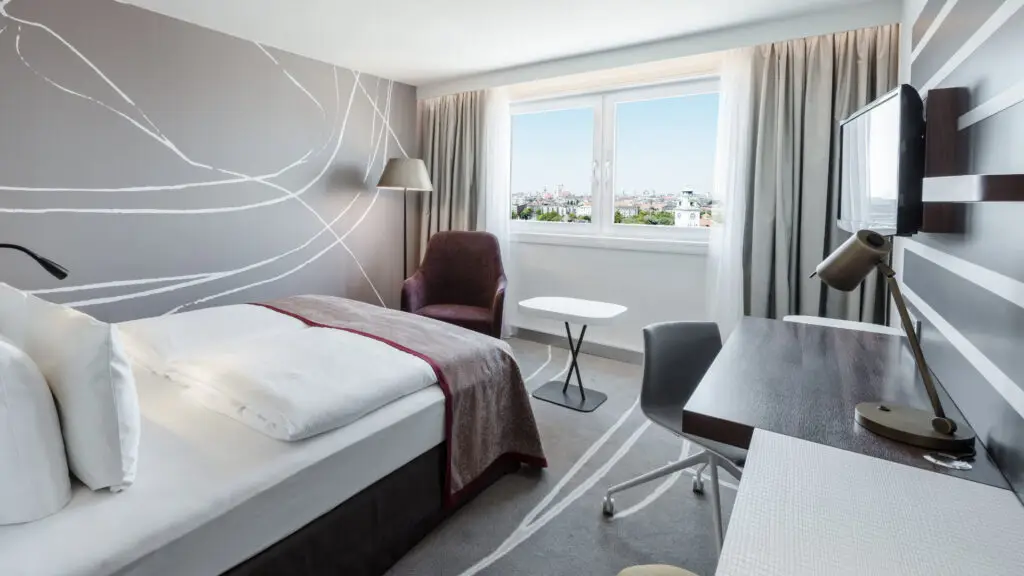 Hotelzimmer in braun und rot Tönen mit Panoramablick auf München