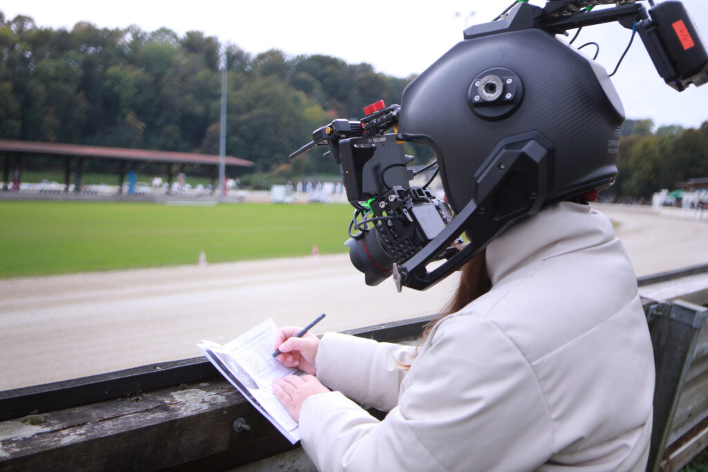 Frau mit einem Kamerahelm die etwas in ein kleines Heft schreibt